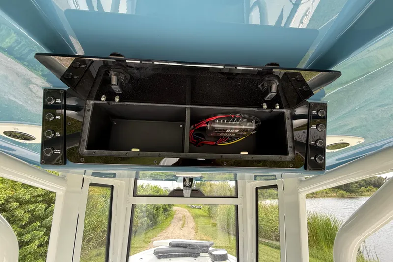 Slide: The Image of Open electronics compartment on 2026 Tidewater 2700 Carolina Bay boat, showcasing wiring and controls. - 39