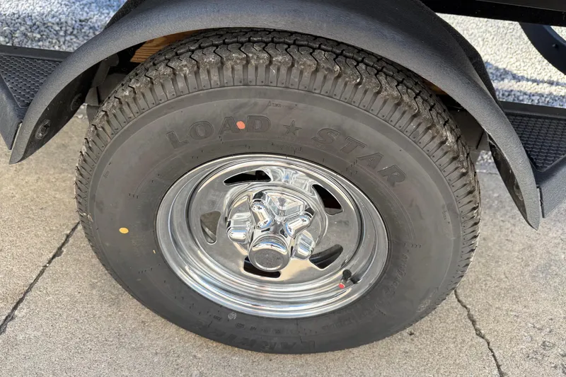 Slide: The Image of 2025 Tracker Pro Team 175 trailer tire with chrome wheel on concrete surface. - 10
