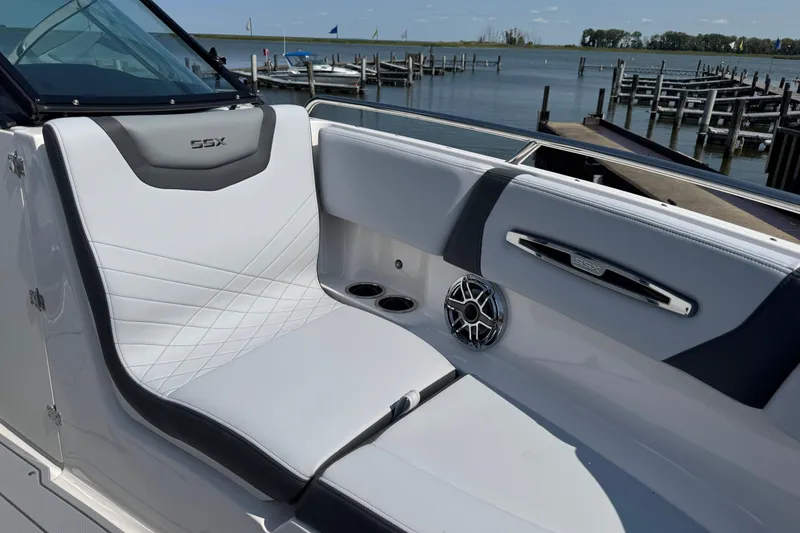 Slide: The Image of 2025 Chaparral 247 SSX boat interior with white seating and speaker, dockside view. - 24
