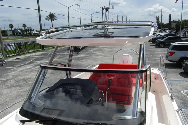 Slide: The Image of 2024 Nimbus T8 boat with red seating and sleek design in a parking lot. - 13