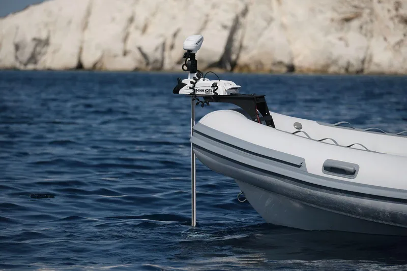 Slide: The Image of 2026 Northstar Vega 5.8 inflatable boat on calm blue sea near rocky coastline. - 6