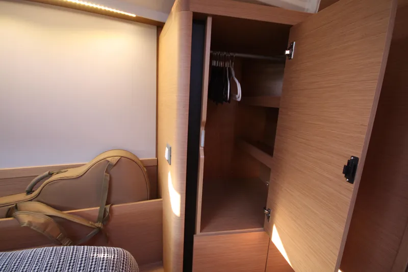 Slide: The Image of Interior of 2022 Jeanneau Sun Odyssey 410 showing open wooden closet and guitar case. - 21