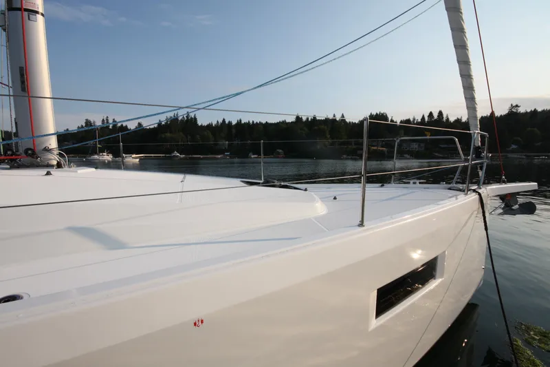 Slide: The Image of 2022 Jeanneau Sun Odyssey 410 sailboat on calm water, showcasing sleek deck design. - 3
