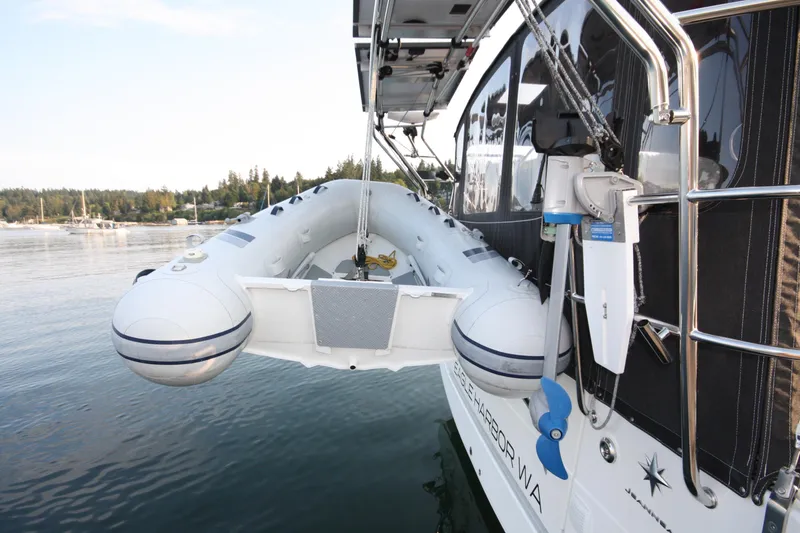 Slide: The Image of 2022 Jeanneau Sun Odyssey 410 with inflatable dinghy on davits, moored in a scenic harbor. - 35