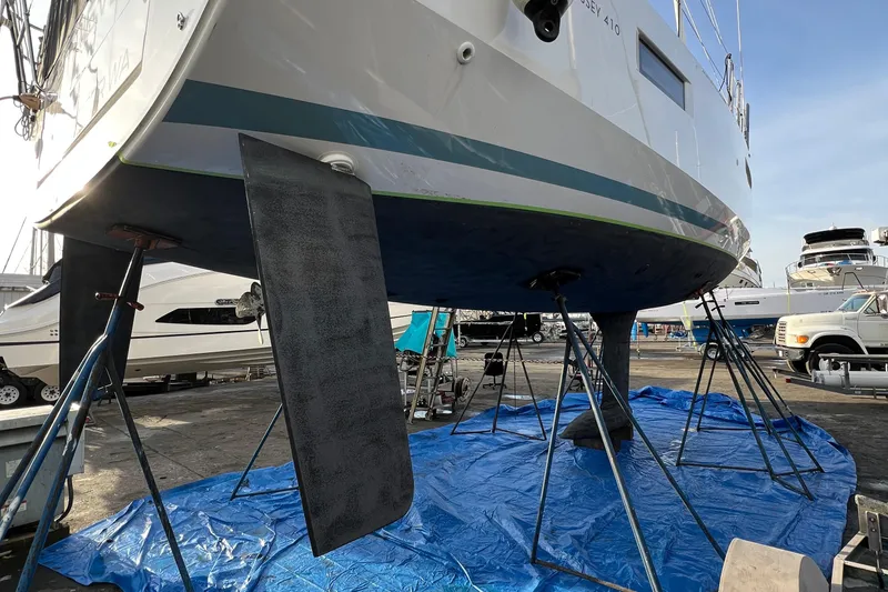 Slide: The Image of 2022 Jeanneau Sun Odyssey 410 sailboat on stands, hull view in a marina. - 44