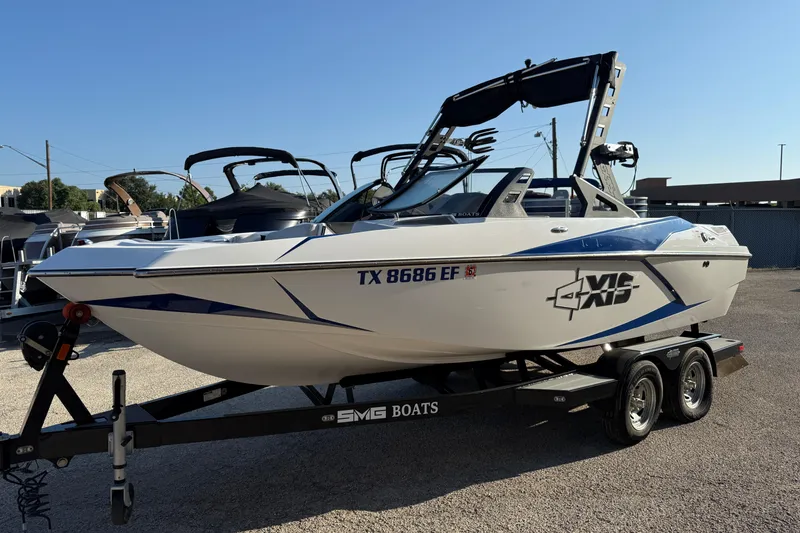 The Image of 2018 Axis A20 boat on trailer, white with blue accents, parked outdoors. - 1