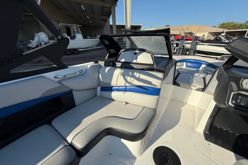 Slide: The Image of 2018 Axis A20 boat interior with blue and white seating, docked in a marina. - 12