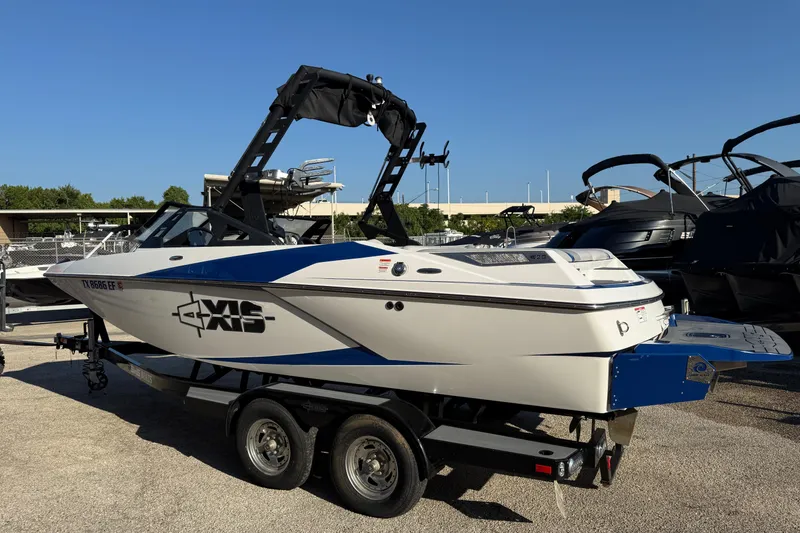 Slide: The Image of 2018 Axis A20 boat on trailer, white with blue accents, parked outdoors. - 24
