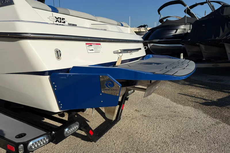 Slide: The Image of 2018 Axis A20 boat with swim platform and blue accents, parked on a trailer. - 3