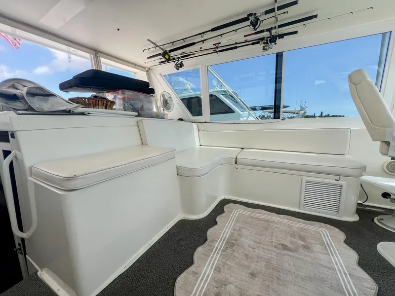 Slide: The Image of Interior of 1996 Viking 60 Cockpit Sport Yacht with white seating and fishing rods. - 18