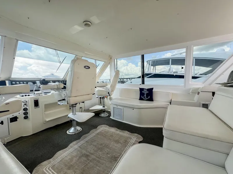 Slide: The Image of 1996 Viking 60 Cockpit Sport Yacht interior with white seating and helm, featuring panoramic windows. - 23