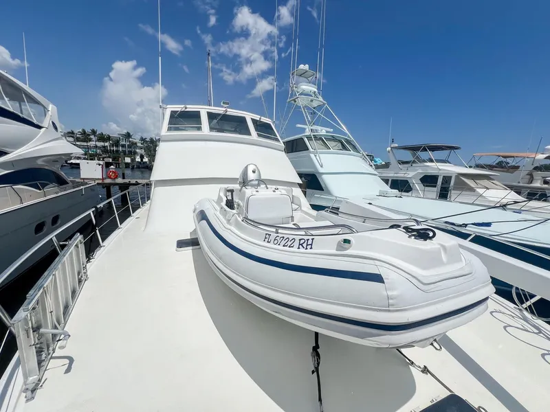 Slide: The Image of 1996 Viking 60 Cockpit Sport Yacht with inflatable boat on deck, docked under clear sky. - 49