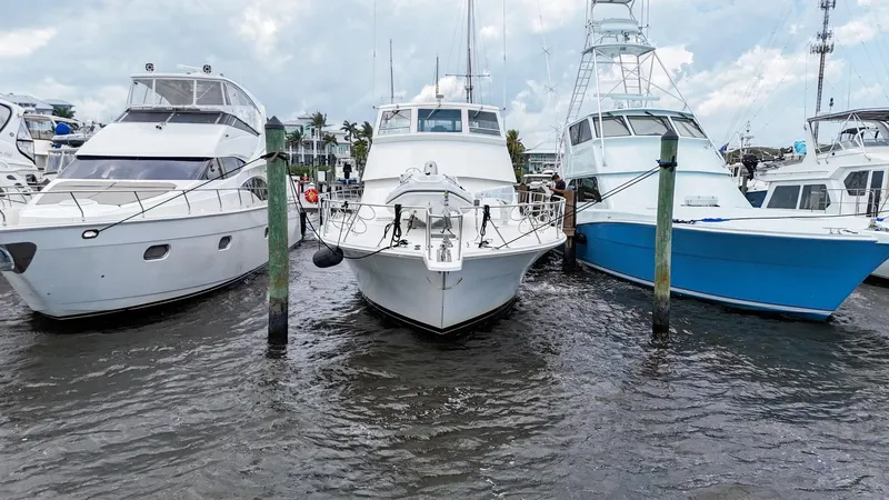 Slide: The Image of 1996 Viking 60 Cockpit Sport Yacht docked between two boats in a marina. - 8