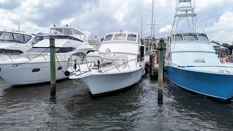 Slide: The Image of 1996 Viking 60 Cockpit Sport Yacht docked among other boats on a cloudy day. - 9