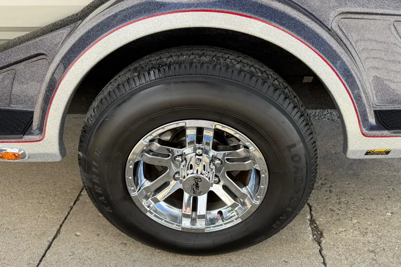 Slide: The Image of 2023 Ranger 1850 Reata trailer wheel with chrome rim and black tire on pavement. - 13