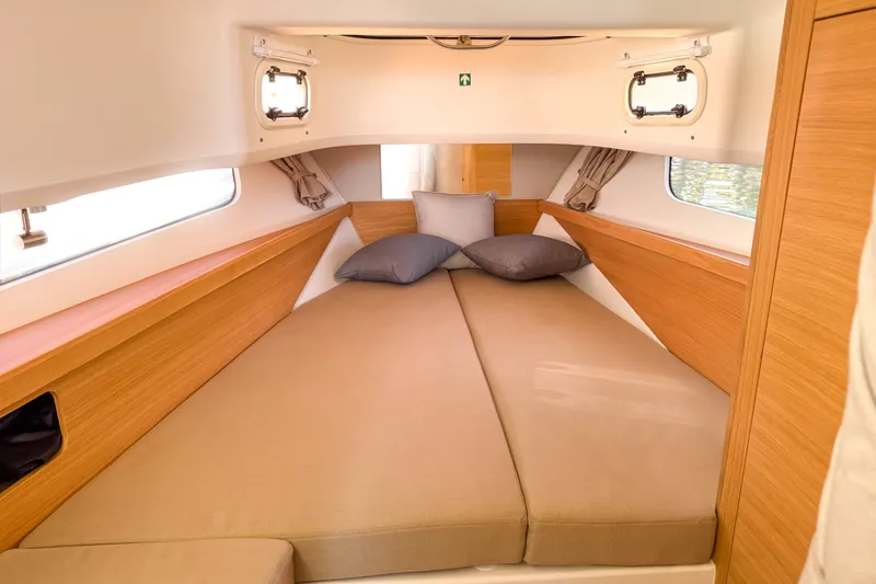 Slide: The Image of Cozy interior cabin of 2025 Nimbus Tender 11 with beige bedding and wooden accents. - 17