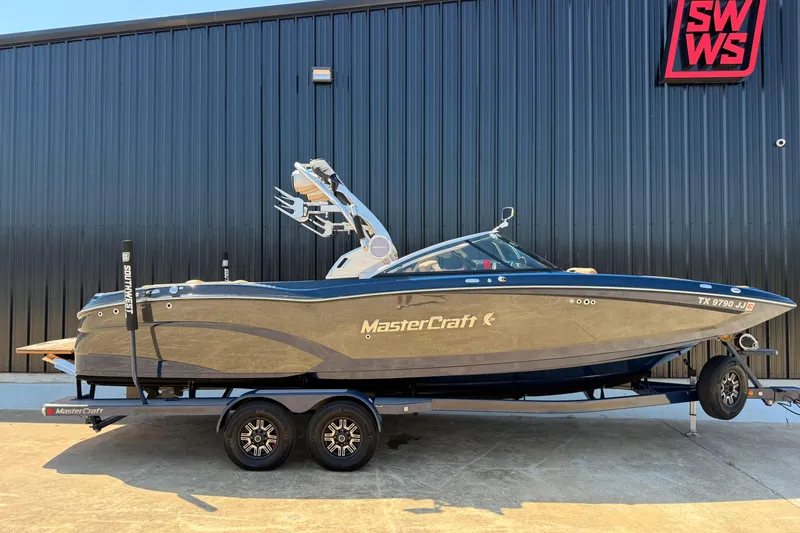 The Image of 2019 MasterCraft X26 boat on trailer, parked outside a black building. - 0