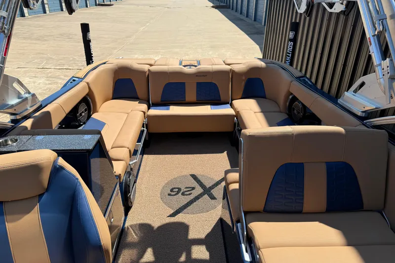 Slide: The Image of 2019 MasterCraft X26 boat interior with tan and blue seating, docked outdoors. - 9