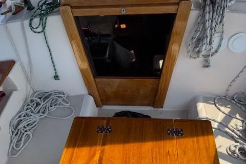 Slide: The Image of 1989 Island Packet 31 sailboat cockpit with wooden hatch and coiled ropes. - 12