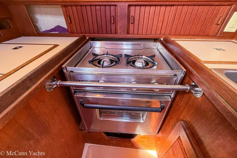 Slide: The Image of 1989 Island Packet 31 yacht kitchen with stainless steel stove and wooden cabinetry. - 20