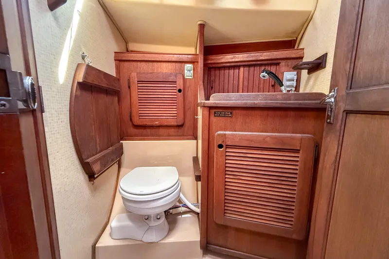 Slide: The Image of 1989 Island Packet 31 boat bathroom with wooden cabinetry and compact toilet. - 27