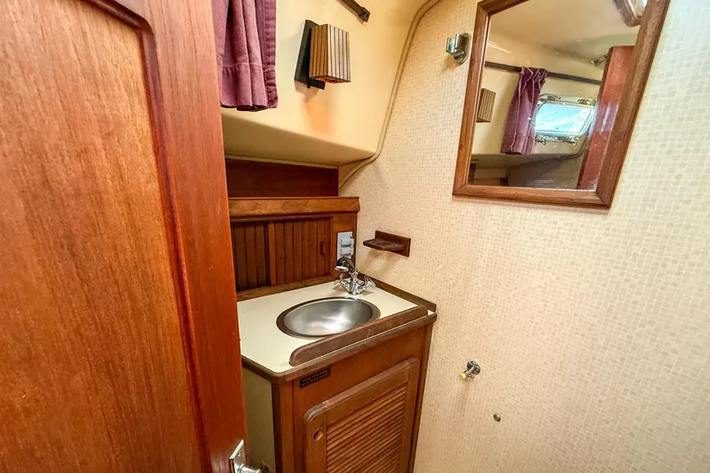 Slide: The Image of 1989 Island Packet 31 yacht bathroom with wooden cabinetry, sink, and mirror. - 28
