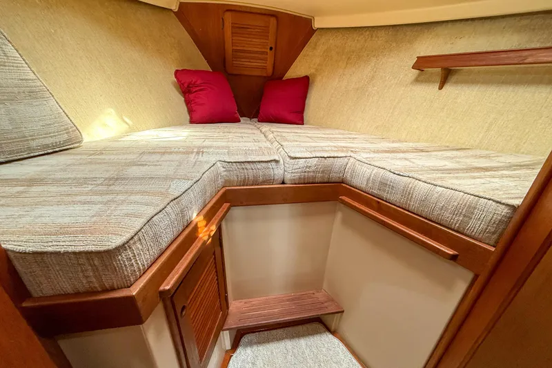 Slide: The Image of Cozy cabin interior of 1989 Island Packet 31 sailboat with cushioned berth and wooden accents. - 32