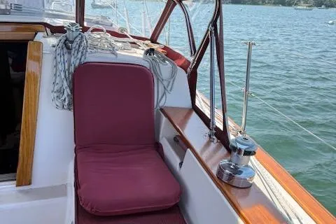 Slide: The Image of 1989 Island Packet 31 sailboat cockpit with maroon cushions, docked by the water. - 35