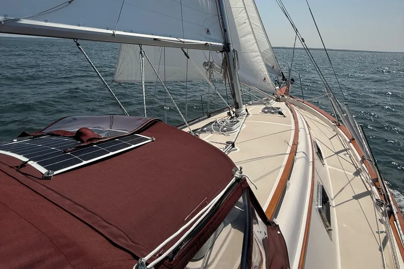 Slide: The Image of 1989 Island Packet 31 sailboat with solar panel, sailing on open water. - 36