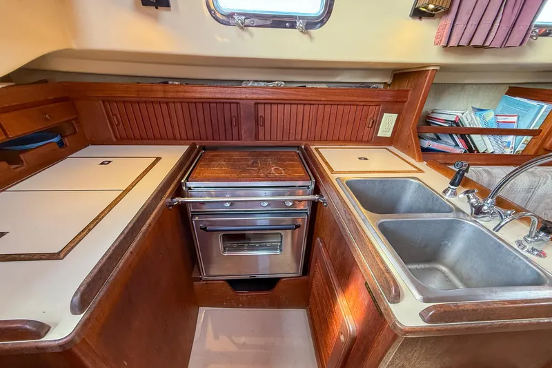 Slide: The Image of 1989 Island Packet 31 yacht kitchen with stove, double sink, and wooden cabinetry. - 43