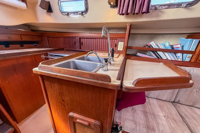 Slide: The Image of 1989 Island Packet 31 yacht interior with wooden cabinetry, sink, and cozy seating area. - 44