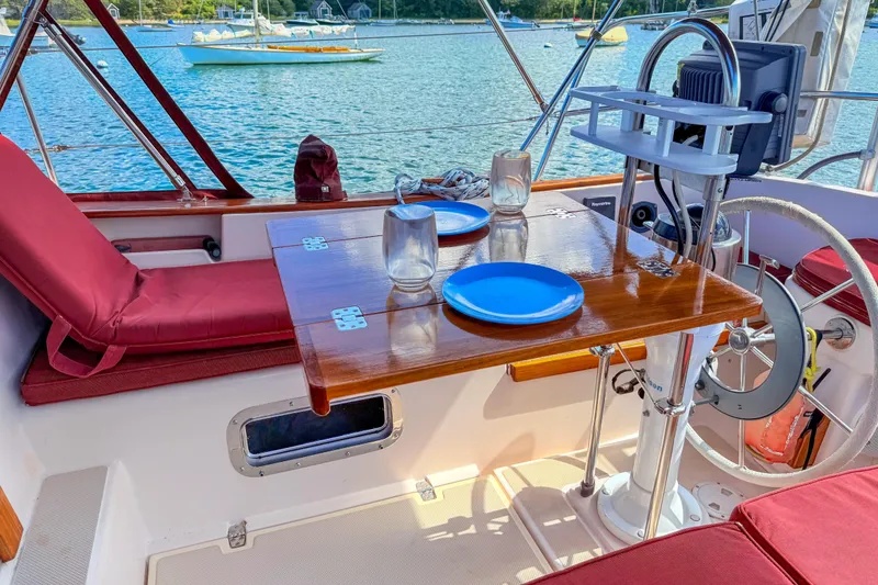 Slide: The Image of Cozy cockpit of 1989 Island Packet 31 sailboat with dining setup and scenic water view. - 6