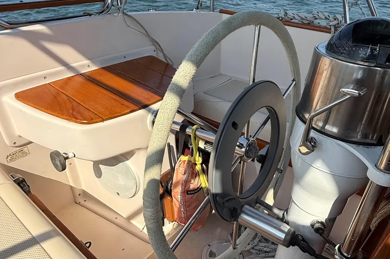 Slide: The Image of 1989 Island Packet 31 sailboat cockpit with wooden seating and steering wheel. - 9