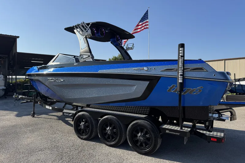 Slide: The Image of 2019 Tigé ZX5 boat on trailer, blue and gray design, parked outdoors. - 2