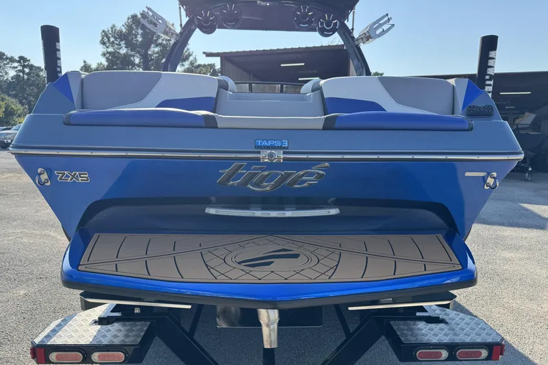 Slide: The Image of 2019 Tigé ZX5 boat rear view, blue color, on trailer, outdoor setting. - 3