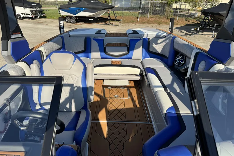 Slide: The Image of 2019 Tigé ZX5 boat interior with blue and white seating, wood flooring, and steering wheel. - 9
