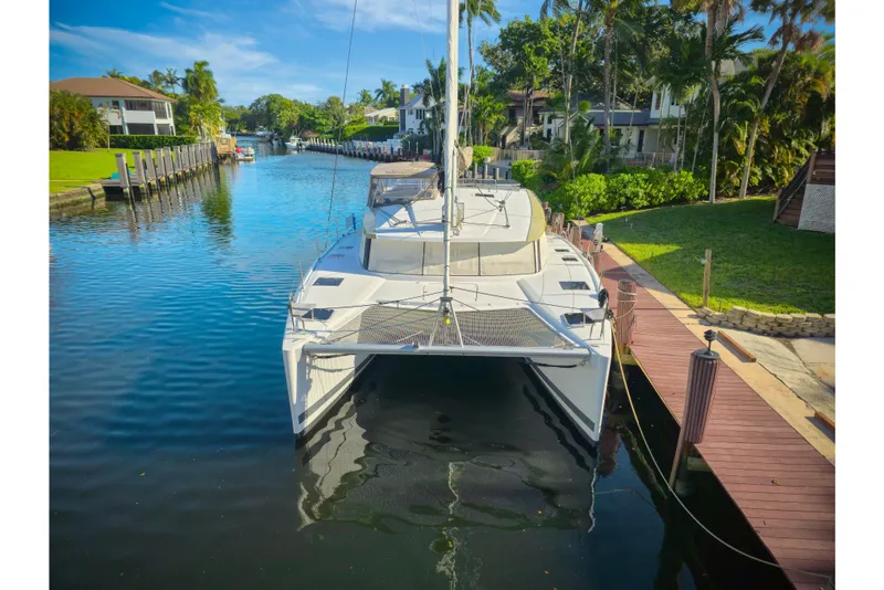 Slide: The Image of 2017 Fountaine Pajot Lucia 40 catamaran docked in a scenic canal setting. - 1
