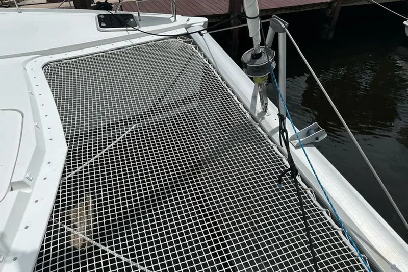 Slide: The Image of 2017 Fountaine Pajot Lucia 40 catamaran with netting on deck, docked by water. - 13