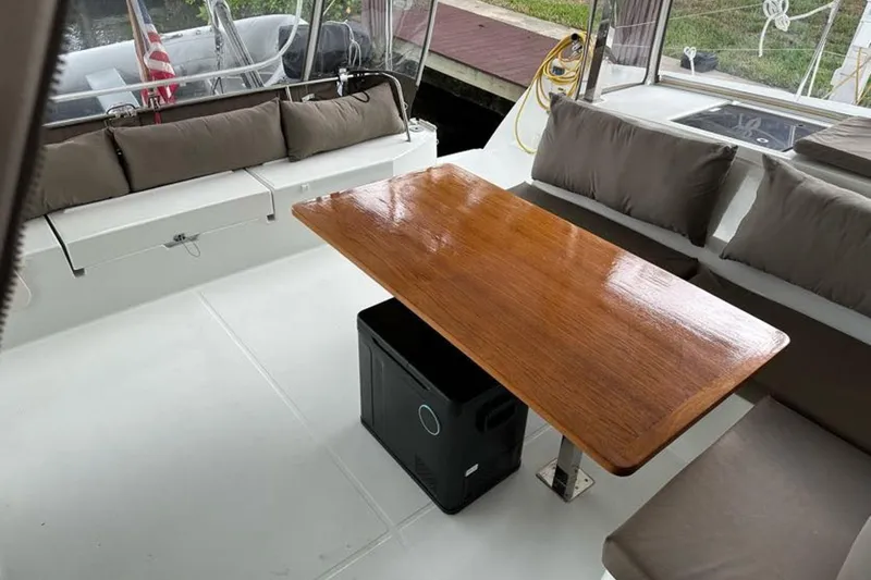 Slide: The Image of 2017 Fountaine Pajot Lucia 40 catamaran cockpit with wooden table and cushioned seating. - 40