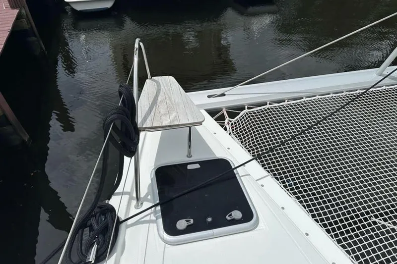 Slide: The Image of 2017 Fountaine Pajot Lucia 40 catamaran deck with netting and ropes, docked by water. - 8