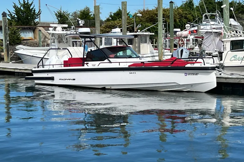 The Image of 2021 Axopar 28 boat docked at marina, featuring sleek design and red seating. - 1