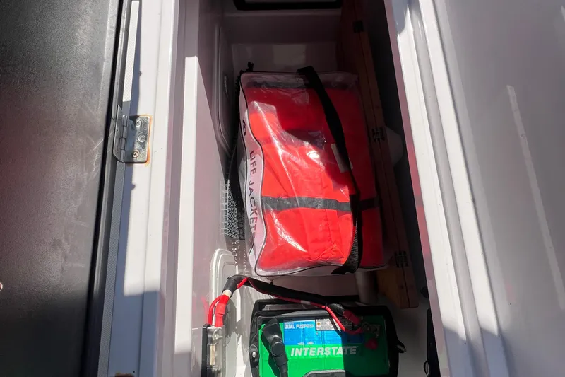 Slide: The Image of Storage compartment in a 2021 Axopar 28 with life jacket and battery. - 12