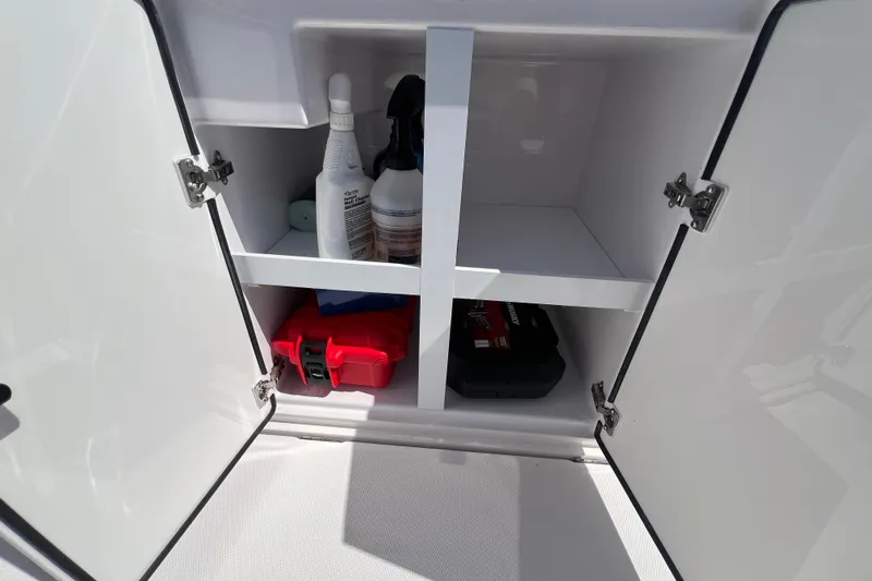 Slide: The Image of Open storage cabinet on 2021 Axopar 28 boat with cleaning supplies and tools. - 16