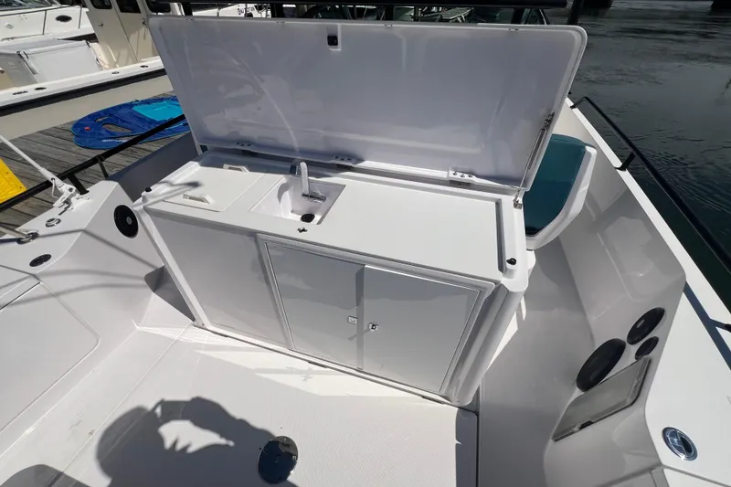 Slide: The Image of 2021 Axopar 28 boat with open storage compartment and sink on deck. - 17