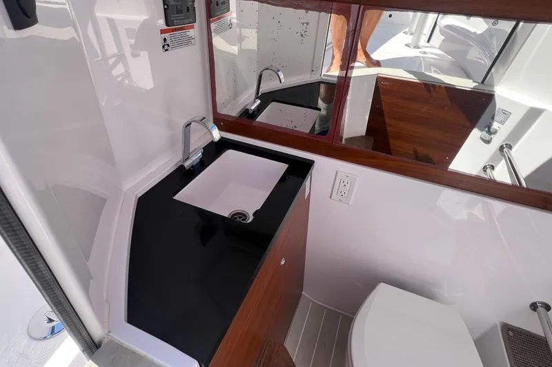 Slide: The Image of 2021 Axopar 28 boat interior bathroom with sink, mirror, and toilet. - 26