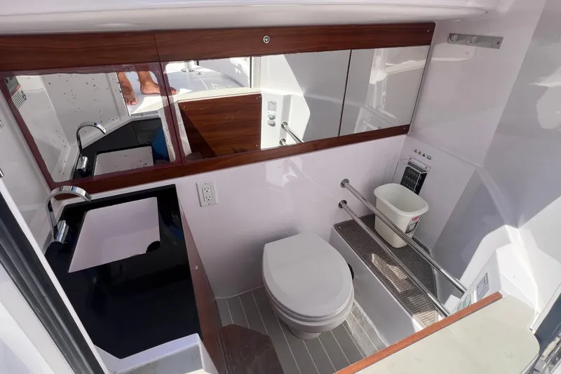 Slide: The Image of 2021 Axopar 28 boat bathroom with modern fixtures and wood accents. - 27