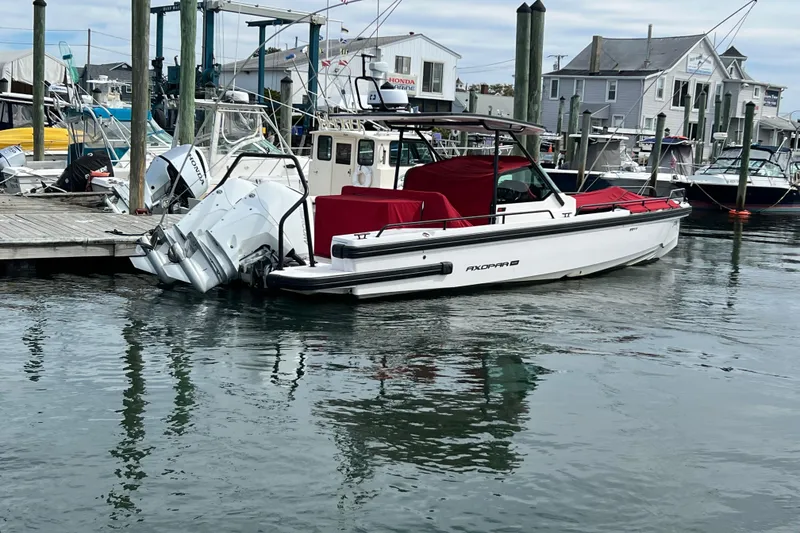 Slide: The Image of 2021 Axopar 28 boat docked at marina with red cover and twin outboard engines. - 3