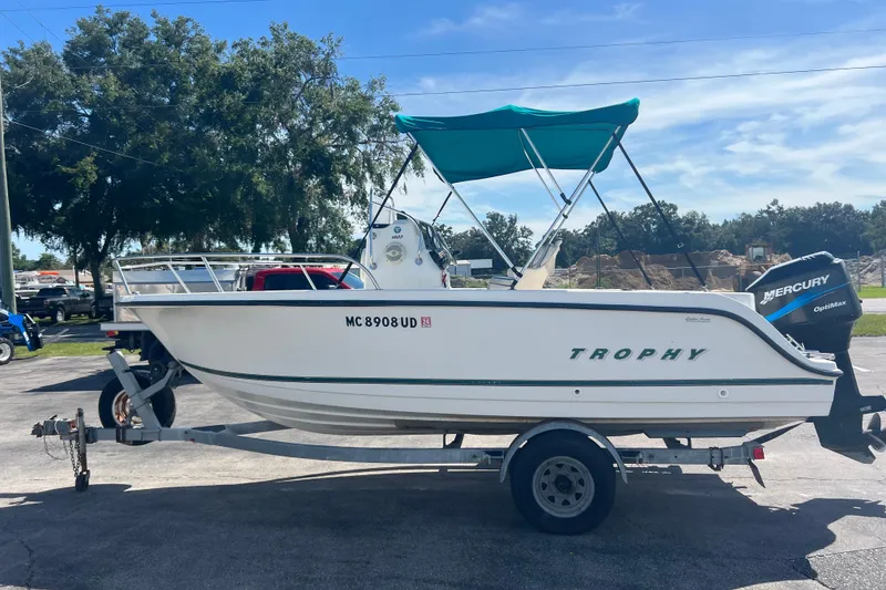 Slide: The Image of 2001 Trophy 1903 Center Console boat on trailer with Mercury engine, parked outdoors. - 5