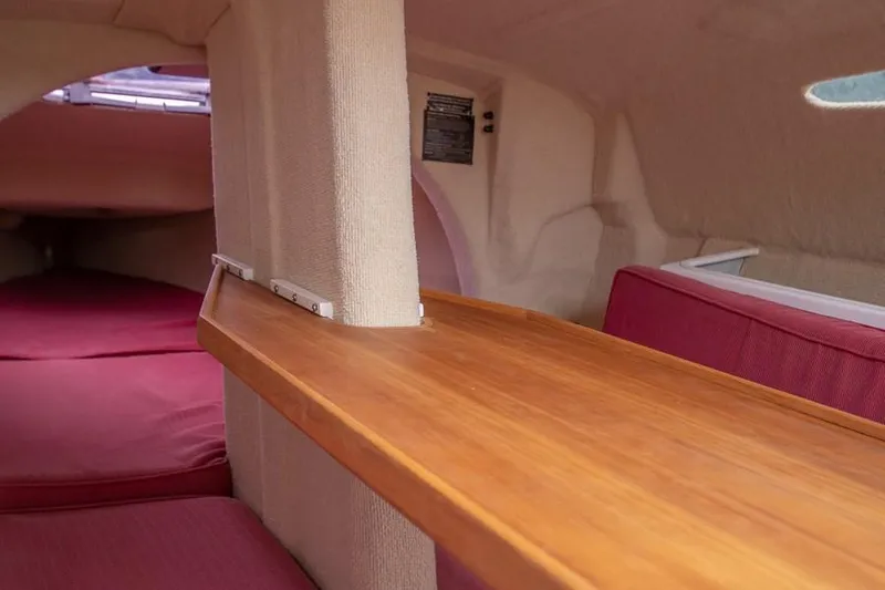 Slide: The Image of Interior of 2010 Corsair Dash 750 sailboat with wooden table and red seating. - 6