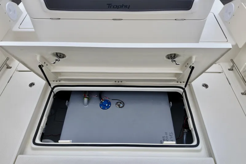 Slide: The Image of 2026 Bayliner Trophy T25 Pilothouse storage compartment with open hatch, showcasing interior details. - 19